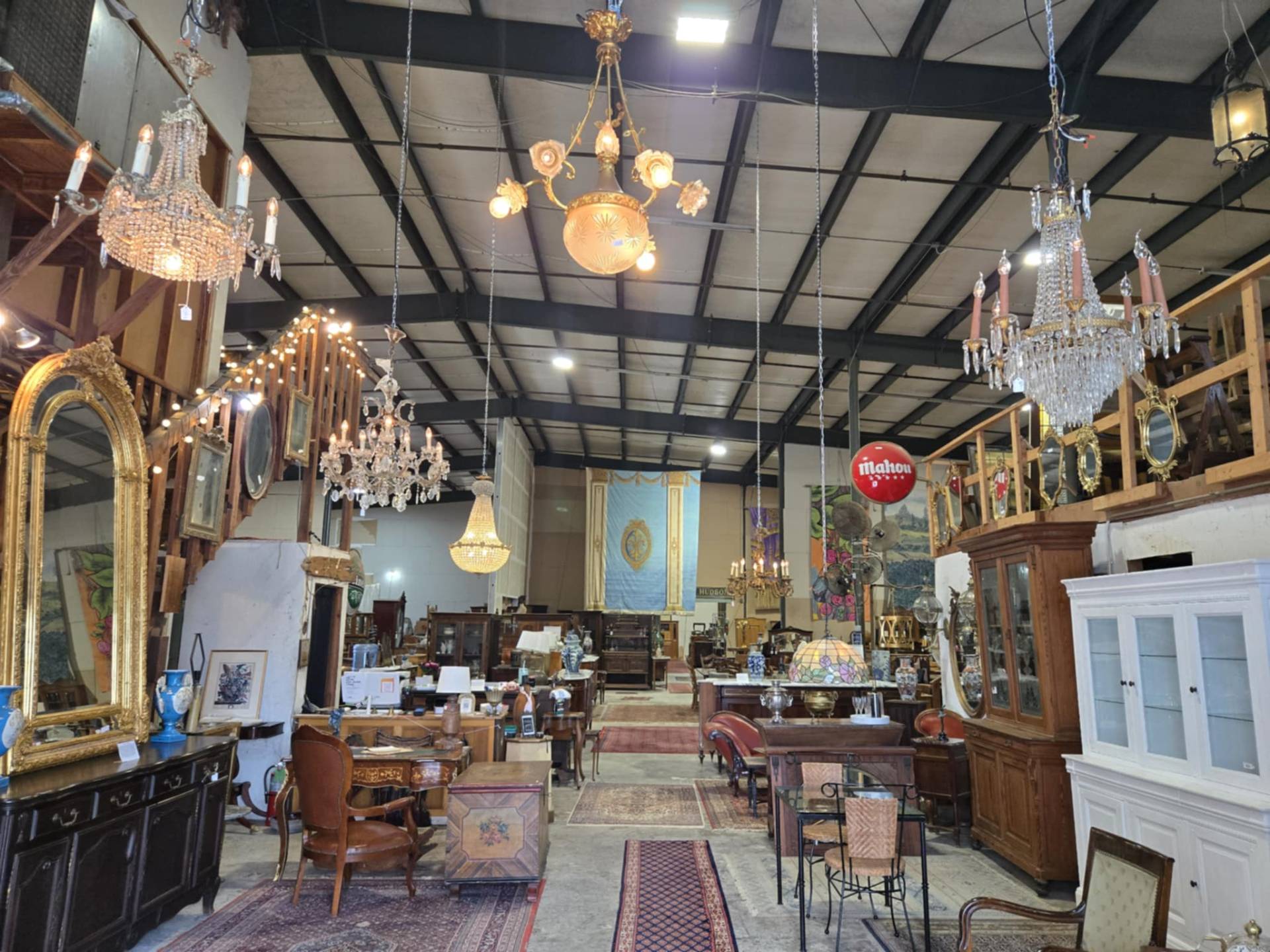 Crystal and gilt chandeliers hanging above gilt mirrors, armoires and case pieces on the DOP Antiques showroom floor in New Orleans.