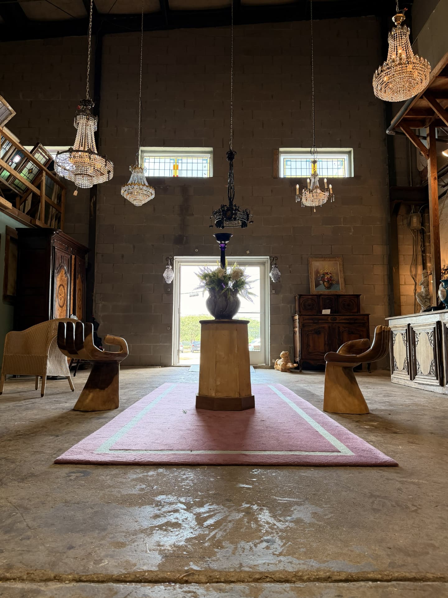 DOP Antiques warehouse showroom interior with crystal chandeliers, antique furniture, and a central floral arrangement on a pedestal