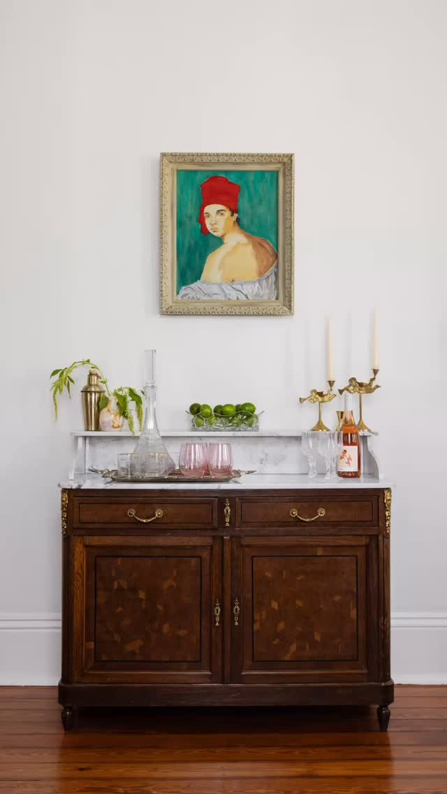 Antique French walnut buffet with marble top styled as a bar, with brass bird candlesticks and a framed portrait above
