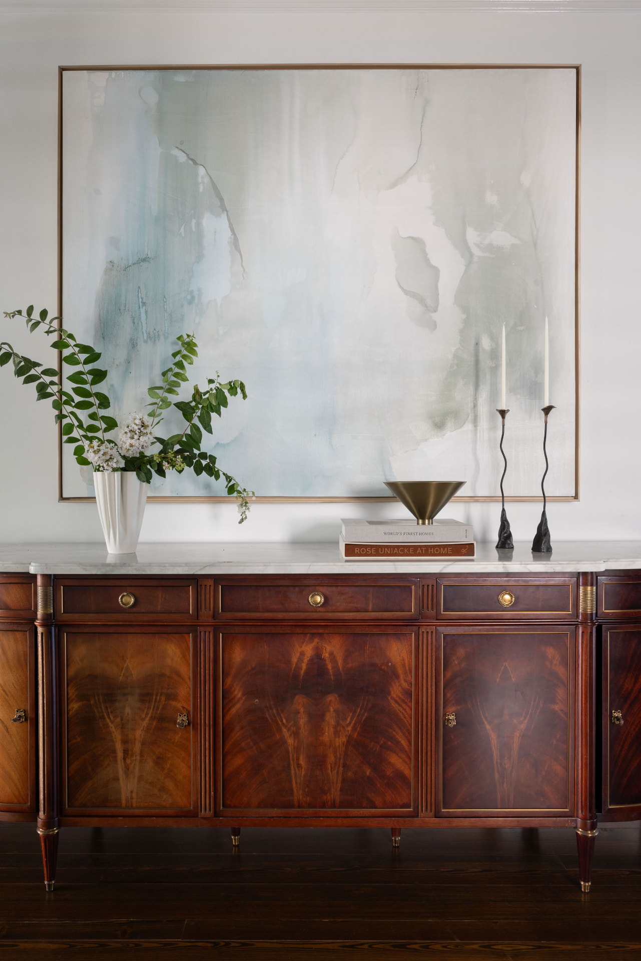 Flame-mahogany antique sideboard with brass mounts and a marble top beneath a large abstract painting