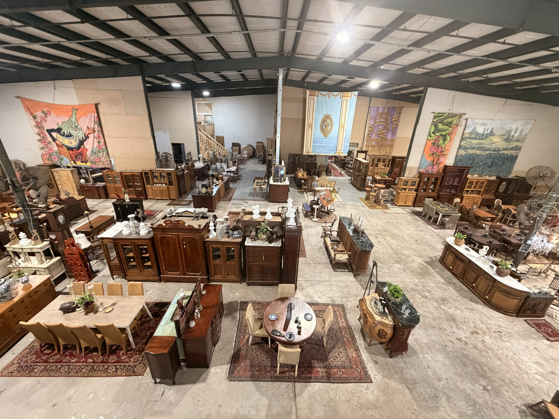 Overhead view of the showroom with painted theatre backdrops and aisles of antique furniture