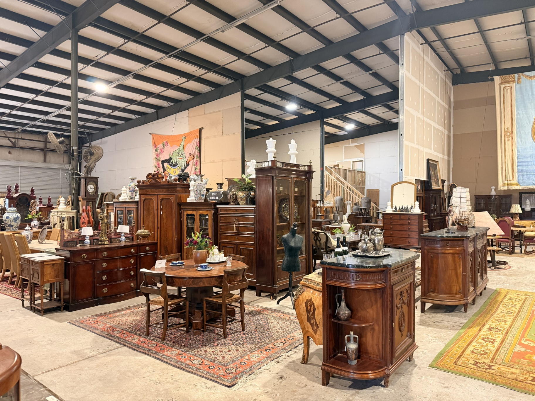 Rows of walnut and mahogany armoires, sideboards and dining tables in the warehouse showroom